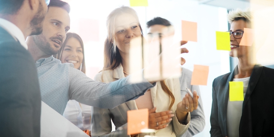 Eine Gruppe von Menschen vor einer Glaswand mit Post-its