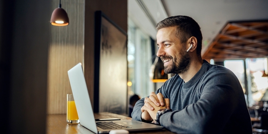 Ein Mann sitzt mit Kopfhörern vor einem Laptop